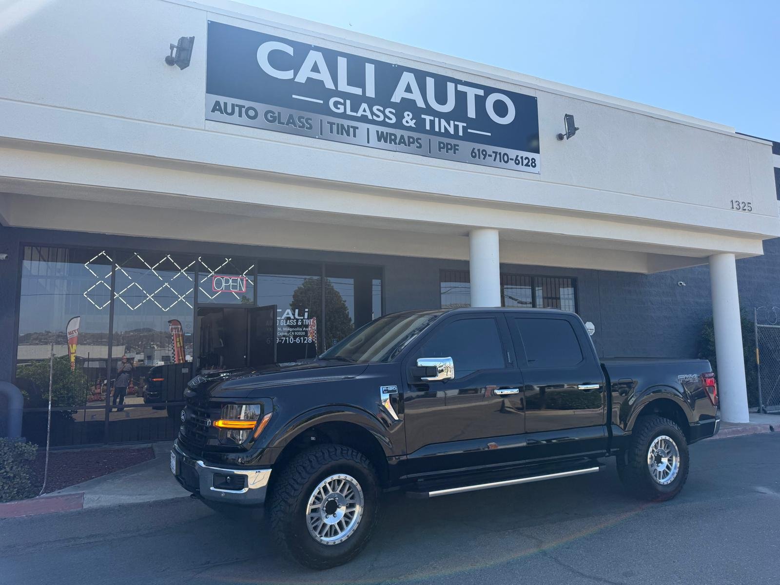 Black Ford F-150 FX4 pickup truck after window tint installation outside Cali Auto Glass and Tint in El Cajon