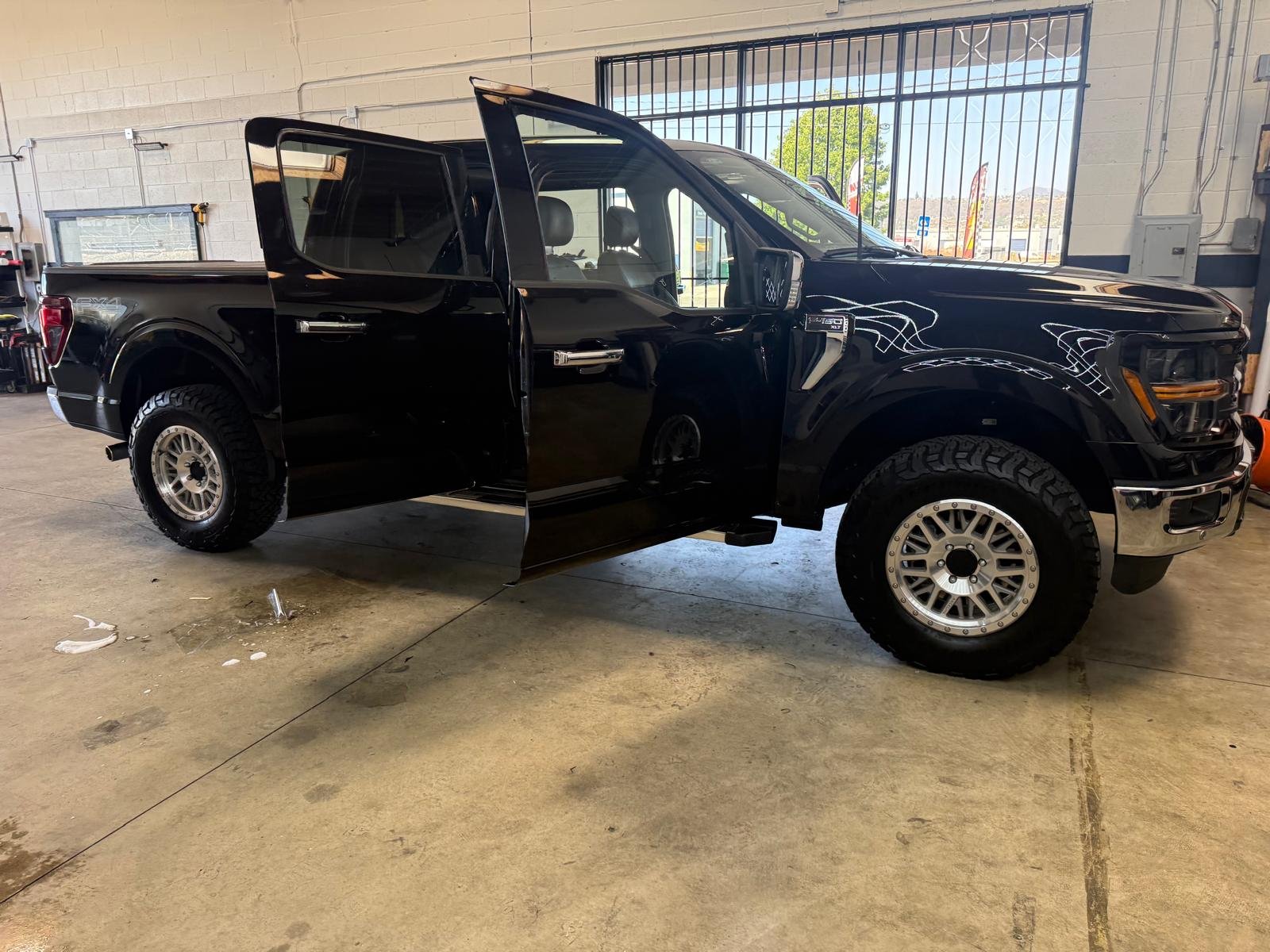 Black Ford F-150 FX4 truck with driver door open during window tint installation at Cali Auto Glass and Tint in El Cajon